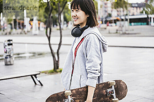 Weiblicher Teenager mit Skateboard auf Fußweg