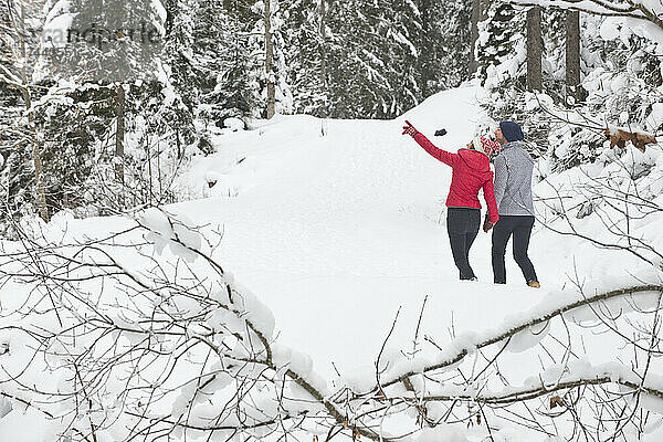 Frau gestikuliert beim Spaziergang mit Mann im Schnee