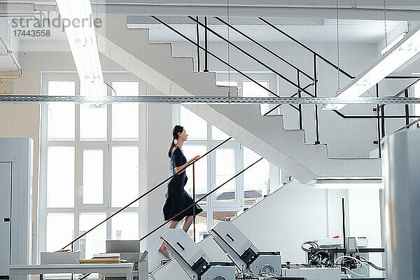 Geschäftsfrau steigt in der Werkstatt die Treppe hinauf