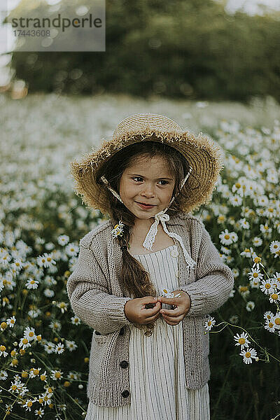 Mädchen mit Hut steht am Blumenfeld