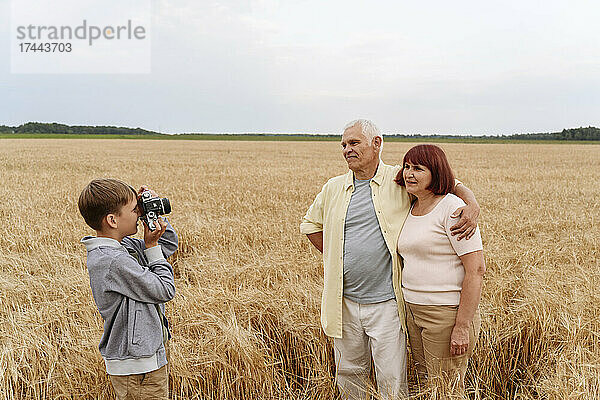 Enkel fotografiert Großeltern mit der Kamera im Weizenfeld
