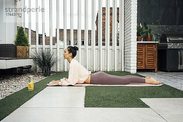 Frau praktiziert Yoga  während sie auf einer Trainingsmatte liegt