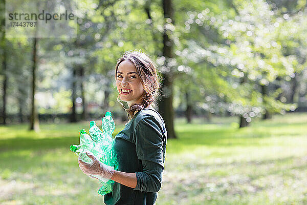 Umweltschützerin hält Plastikflaschen im Park