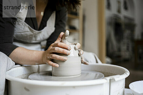 Kunsthandwerkerin formt Ton auf Töpferscheibe in Werkstatt