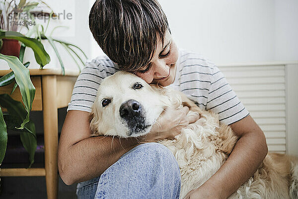 Frau mittleren Alters umarmt Hund zu Hause
