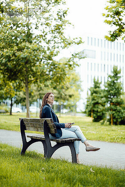 Junge Geschäftsfrau sitzt auf einer Bank im Park