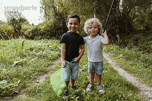 Süße Jungs stehen auf Gras und halten Birnen im Fischernetz