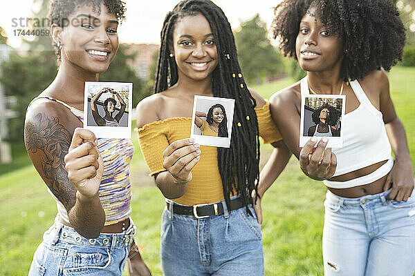 Lächelnde junge Frauen zeigen Fotos im Park
