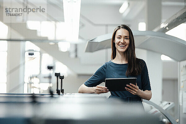 Lächelnde Fachfrau mit digitalem Tablet in der Werkstatt