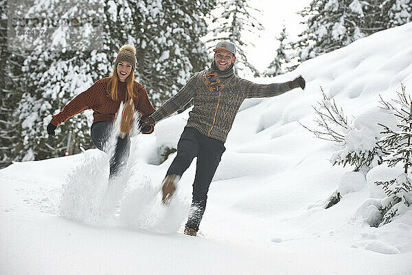 Verspieltes Paar kickt im Winter Schnee