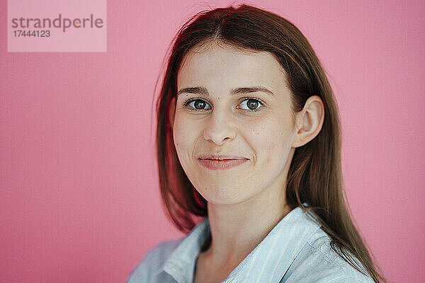 Lächelnde schöne Frau vor rosa Hintergrund