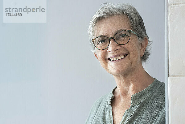 Lächelnde ältere Frau mit Brille zu Hause