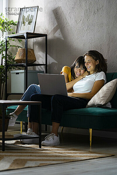 Glückliches lesbisches Paar benutzt Laptop  während es zu Hause sitzt