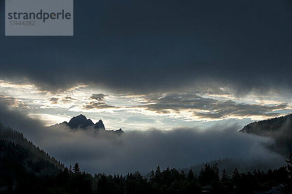 Graue Wolken über dichtem Nebel in den Ennstaler Alpen in der Abenddämmerung