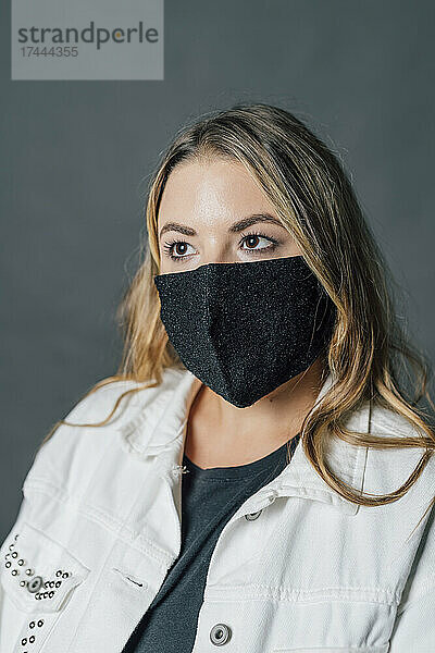 Junge Frau trägt während einer Pandemie eine schützende Gesichtsmaske