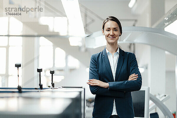 Confident businesswoman standing with arms crossed in industry