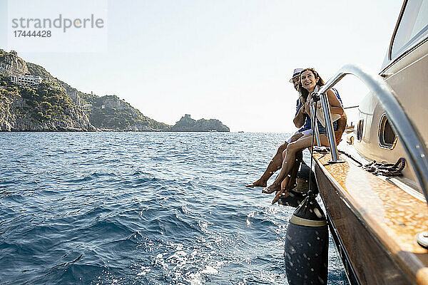 Glückliches Paar sitzt am Rande eines Motorboots an der Amalfiküste  Italien