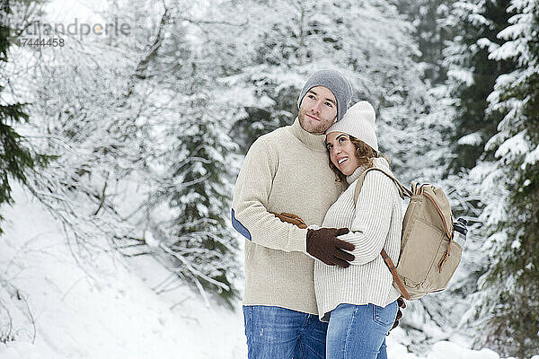 Paar umarmt sich  während es im Winter im Wald steht