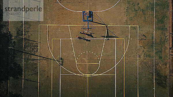 Male friends playing basketball at sports court