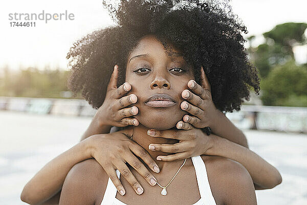 Hände berühren Gesicht einer Afro-Frau