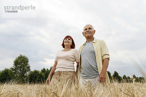 Lächelndes älteres Paar steht im Weizenfeld