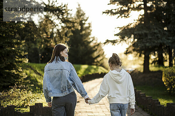Mutter und Tochter halten Händchen beim Spaziergang im Park