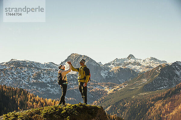 Zwei Wanderer machen High-Five am Gipfel der Ennstaler Alpen
