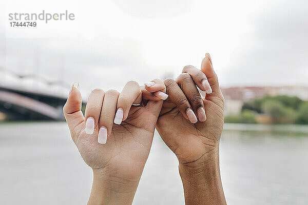 Lesbisches Paar hält Finger am See