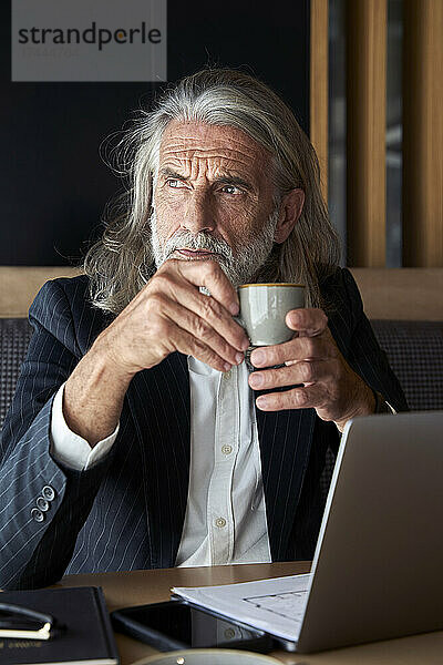 Geschäftsmann mit Kaffeetasse sitzt im Hotelcafé