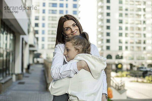 Lächelnde Mutter umarmt Tochter in der Stadt