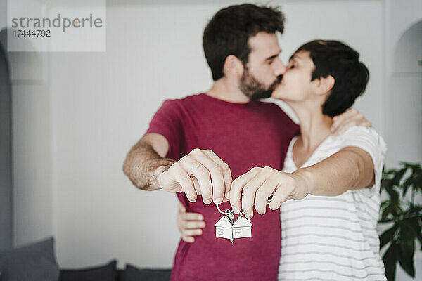 Liebevolles Paar küsst sich  während es den Hausschlüssel in der Hand hält