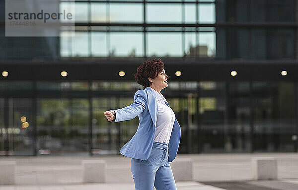 Berufstätige Frau genießt das Tanzen vor dem Bürogebäude