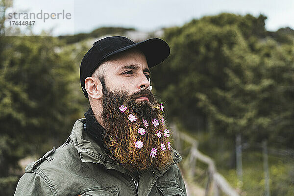 Hipster-Mann mit Blumen im Bart und Mütze