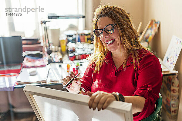 Reife Frau trägt eine Brille beim Malen zu Hause