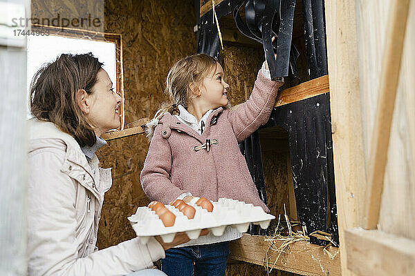 Lächelnde Mutter und Tochter mit Eierkarton im Bio-Bauernhof