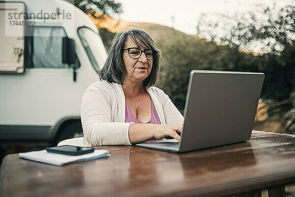 Frau mit Brille und Laptop am Tisch