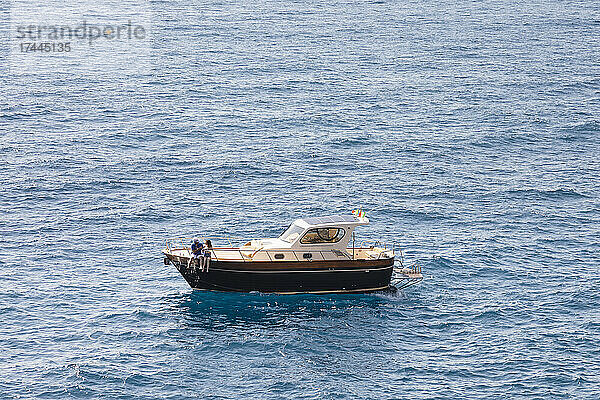 Paar sitzt am Rand eines Motorbootes im Meer