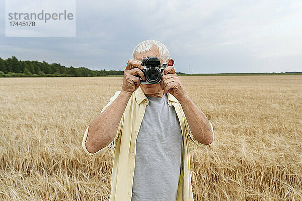 Mann fotografiert mit der Kamera auf Weizenfeld
