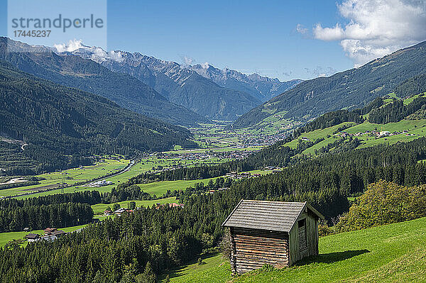 Grünes Bergtal im Sommer mit Hütte im Vordergrund