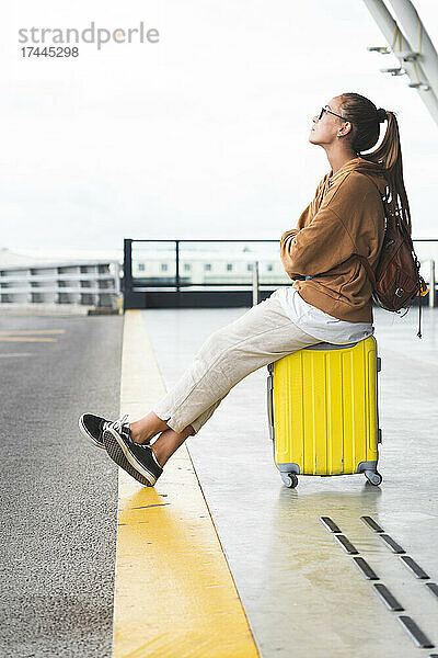 Frau sitzt auf Gepäck am Flughafen