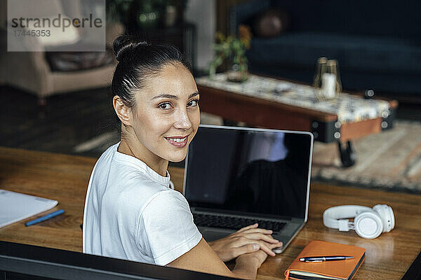 Lächelnde Geschäftsfrau mit Laptop auf dem Schreibtisch