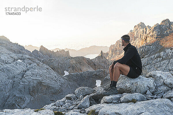 Männlicher Tourist blickt bei Sonnenaufgang auf die Gebirgskette Picos de Europe  Kantabrien  Spanien