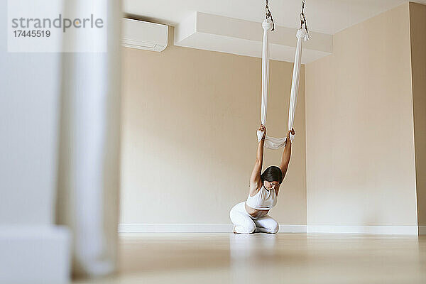 Sportlerin praktiziert Aerial Yoga im Studio