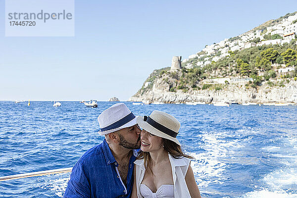 Mann mit Hut küsst Frau an der Amalfiküste  Italien