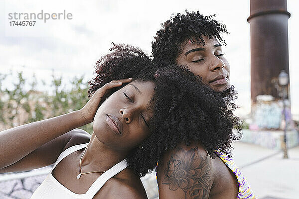 Afro-Frau mit geschlossenen Augen lehnt sich an die Schulter eines Freundes