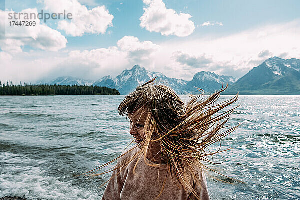 Junges Mädchen wirft an einem sonnigen Tag in der Nähe eines Sees ihre Haare nach draußen