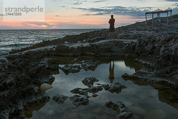 Erwachsener Mann beobachtet den Sonnenuntergang über Porto Roxa  Insel Zakynthos