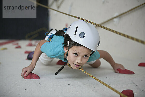 Mädchen klettert an der Indoor-Kletterwand in London