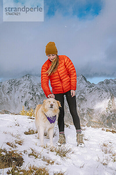 Wanderin und flauschiger Hund auf einem verschneiten Bergrücken