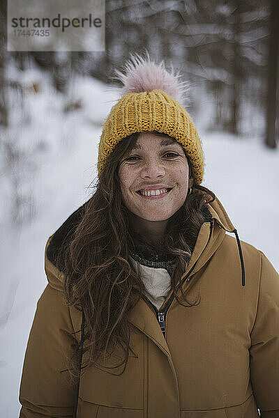 Glückliches Mädchen mit Sommersprossen lächelt im schneebedeckten tschechischen Wald im Winter